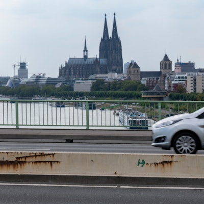 Ein Auto fährt über die Zoobrücke in Köln, im Hintergrund ist der Kölner Dom zu sehen.