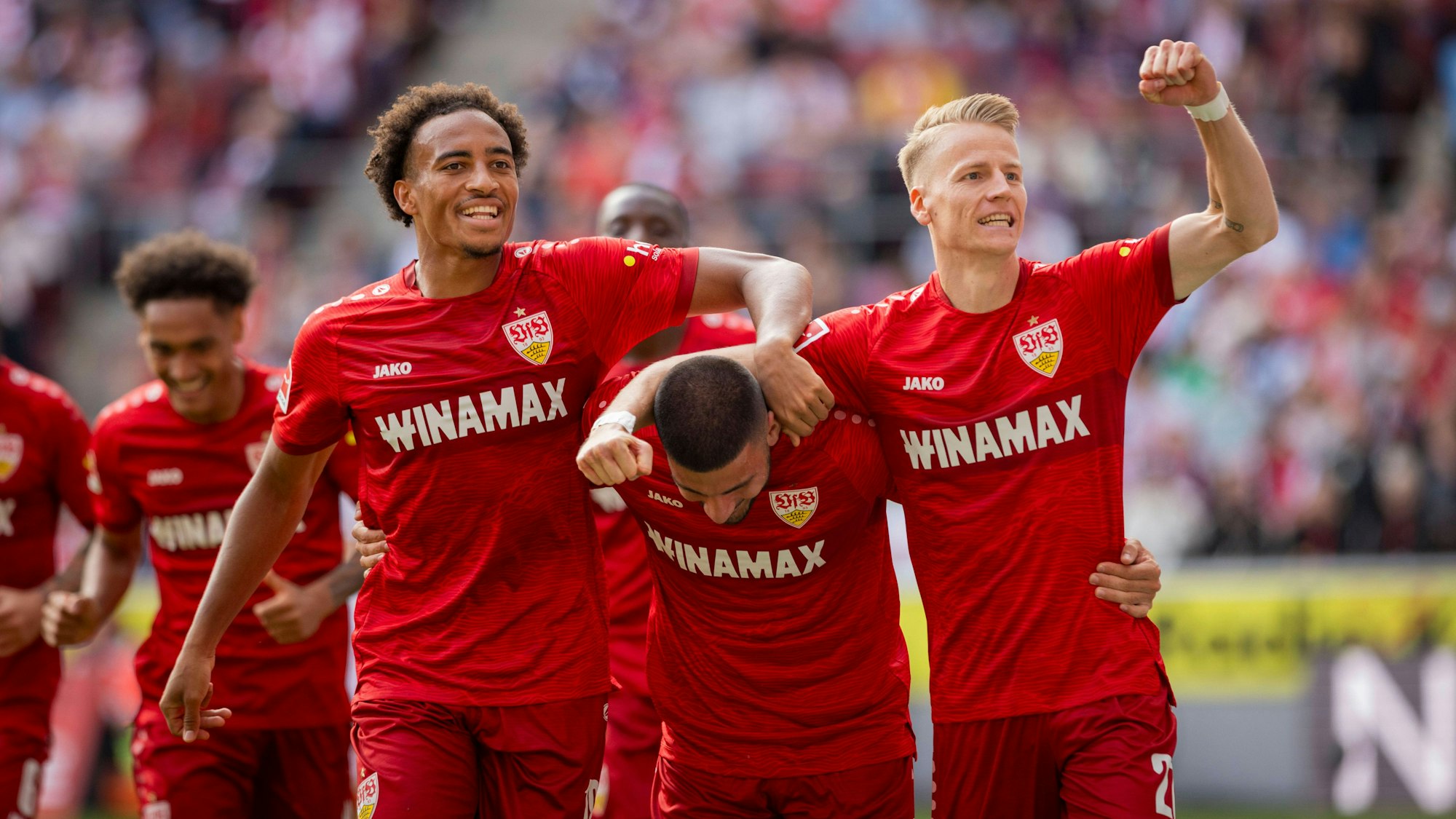 Undav wird von zwei Mitspielern geherzt