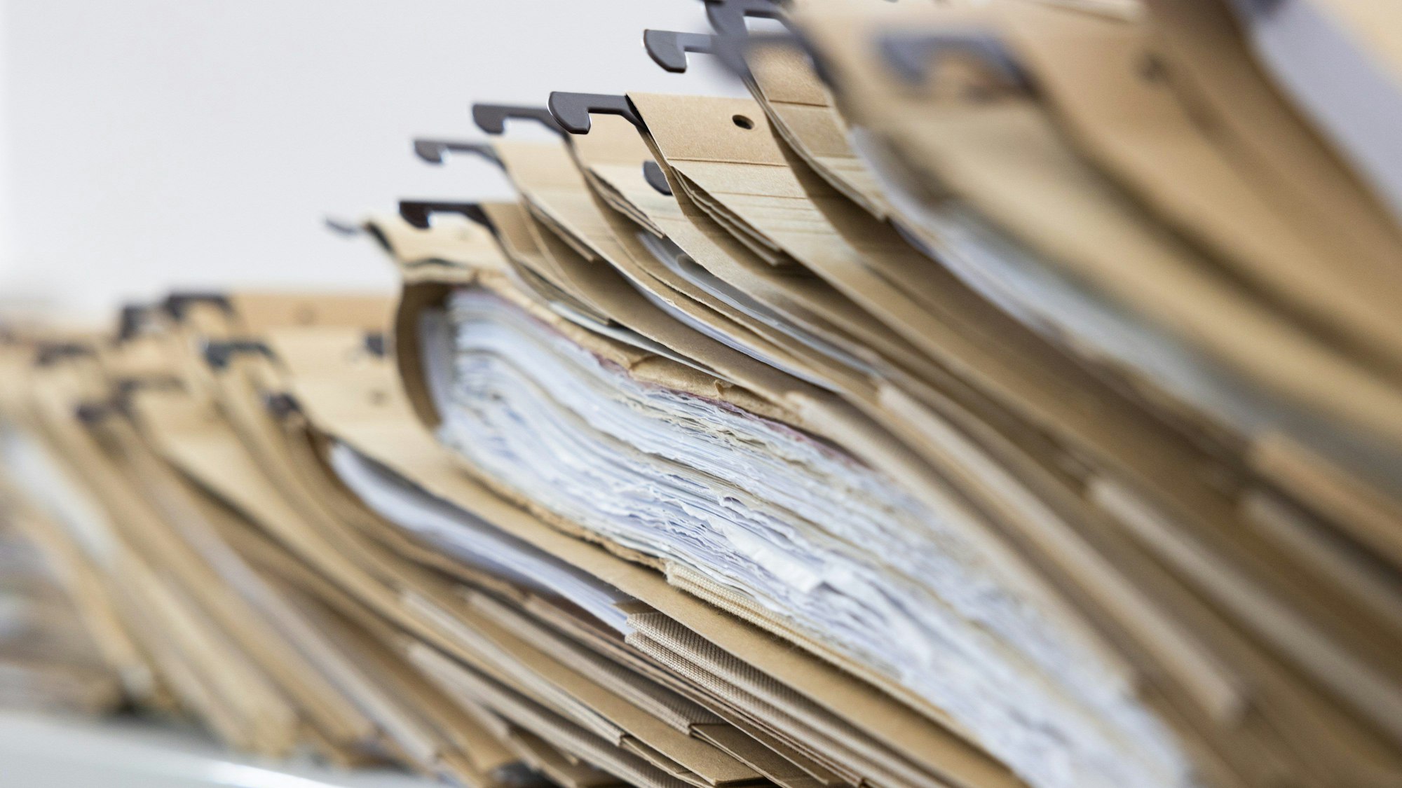 Man sieht Akten, welche unordentlich auf einem Tisch gestapelt sind.