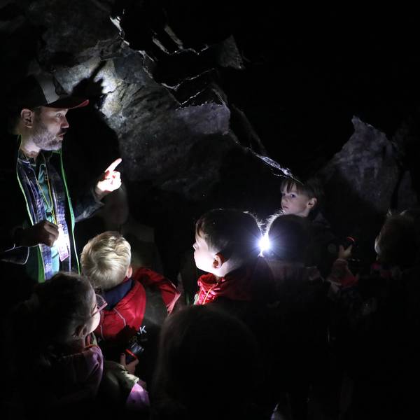 Ein Mann steht mit Kindern in einer Höhle.