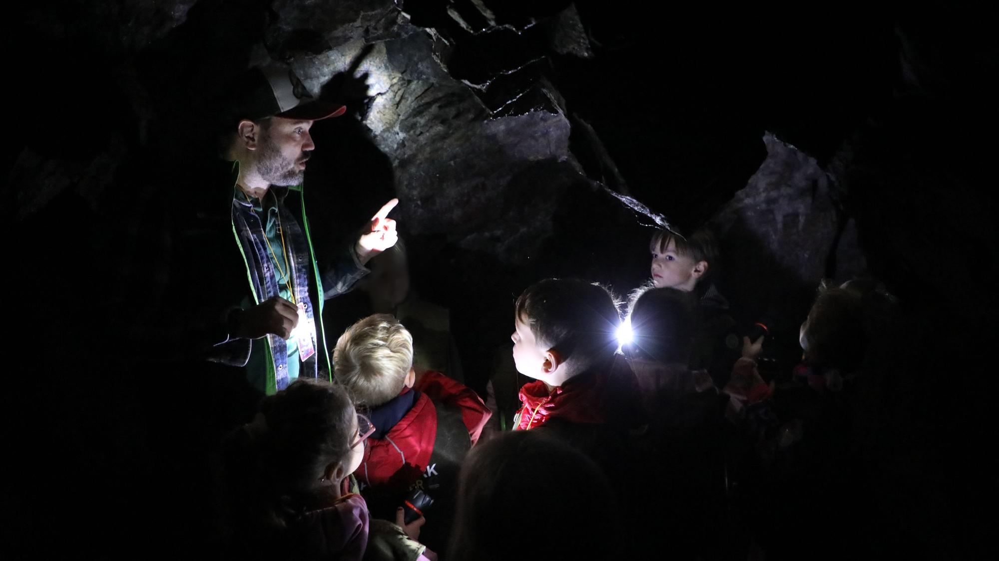 Ein Mann steht mit Kindern in einer Höhle.