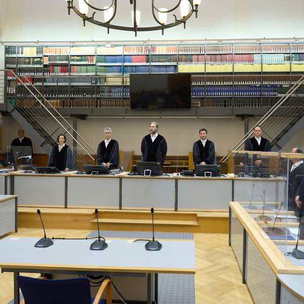 Der Angeklagte (2.v.r) steht zu Prozessbeginn zwischen seinen Anwälten.
