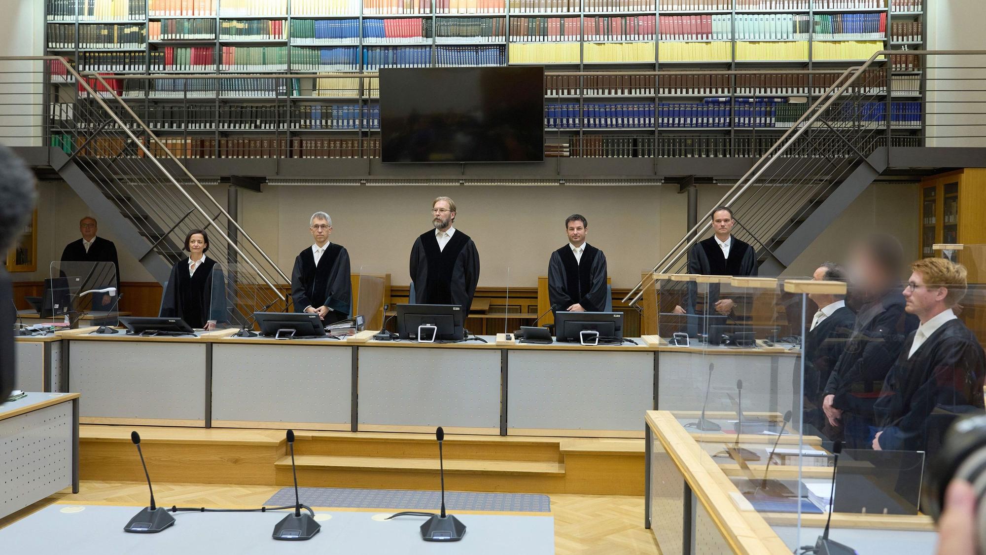 Der Angeklagte (2.v.r) steht zu Prozessbeginn zwischen seinen Anwälten.