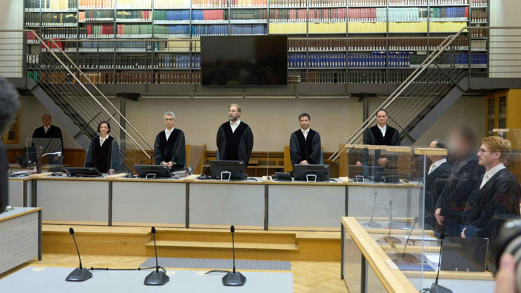 Der Angeklagte (2.v.r) steht zu Prozessbeginn zwischen seinen Anwälten.