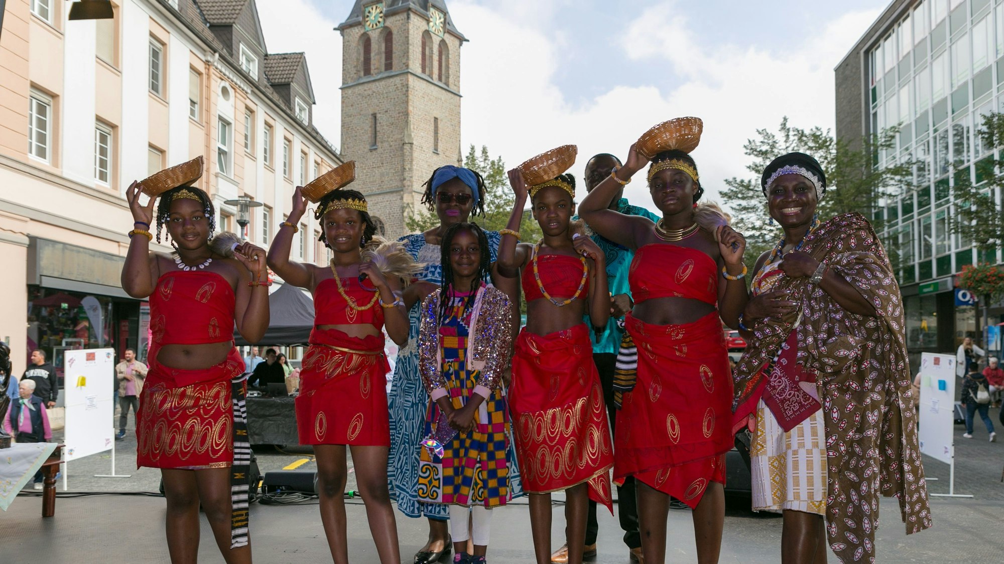 Frauen und Mädchen in bunten Kleidern posieren auf der Bühne auf dem Gummersbacher Lindenplatz, im Hintergrund die katholische Kirche.