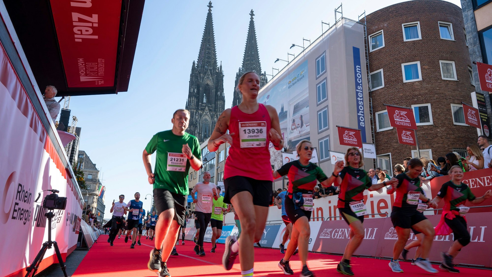 Glück beim Zieleinlauf: Teilnehmerinnen und Teilnehmer erreichen das Ende des Köln Marathons im Schatten des Kölner Doms.