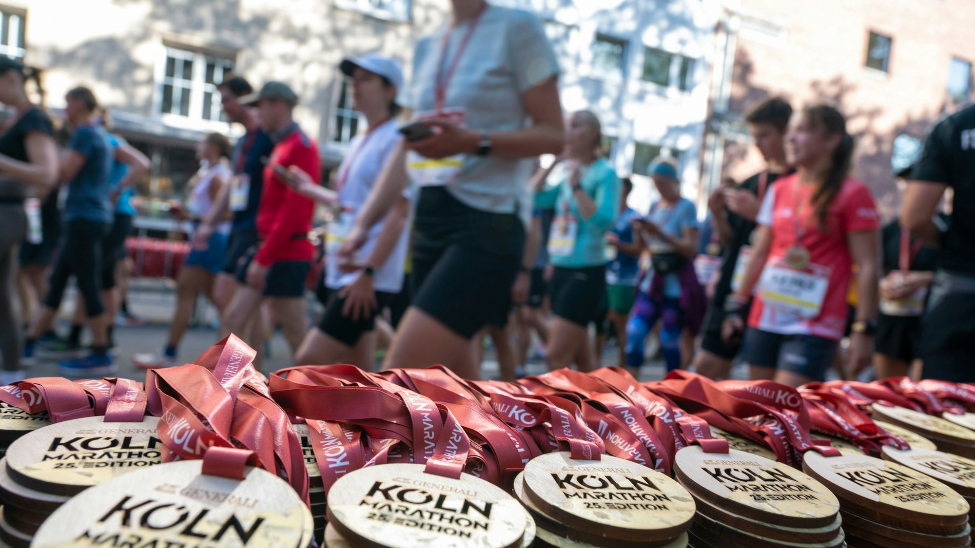 Teilnehmer des Köln-Marathons nehmen ihre Medaillen in Empfang.