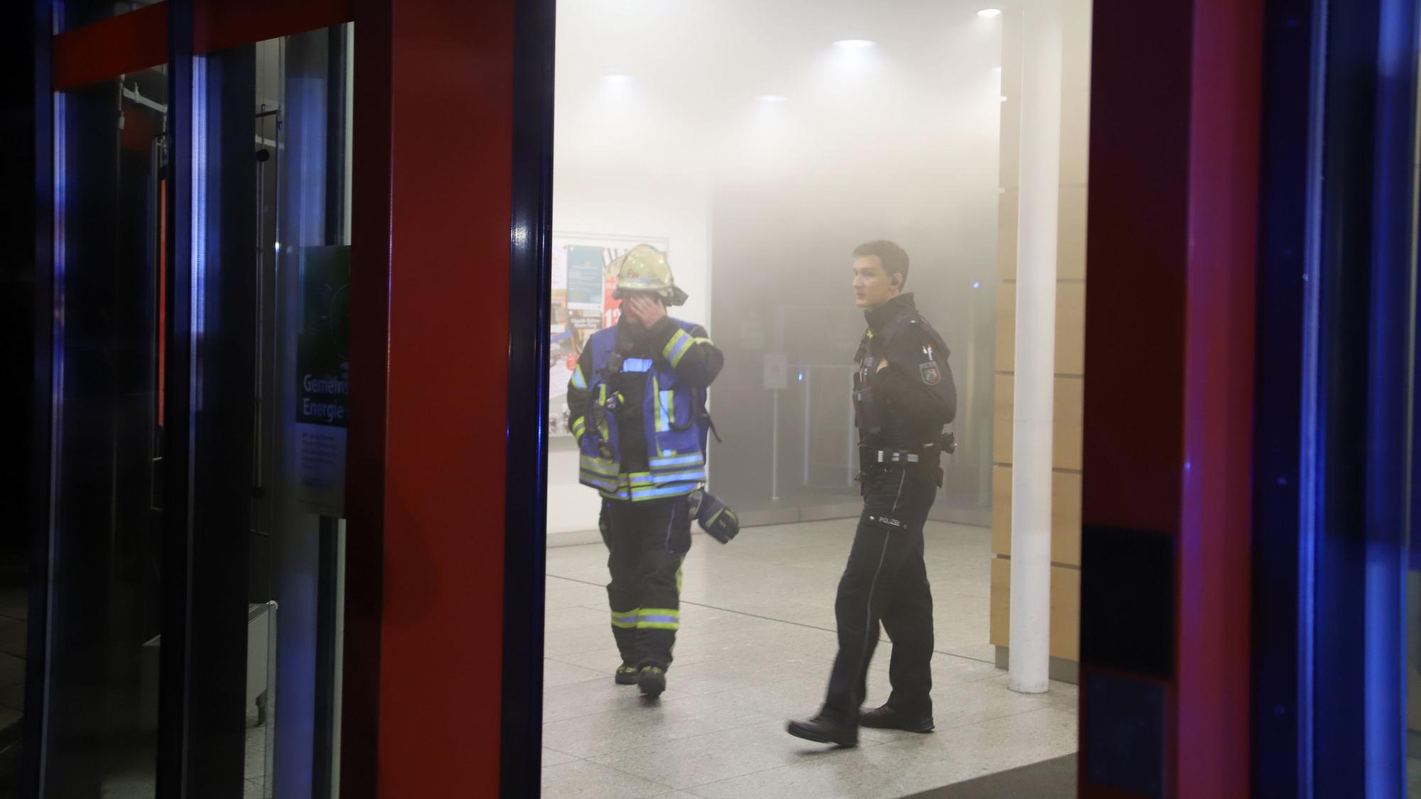 Nach einigen Minuten konnten Polizei und Feuerwehr den Vorraum betreten, Der Feuerwehrmann und der Polizist suchten nach Beschädigungen in dem noch leicht verrauchten Vorraum, entdeckten aber keine.