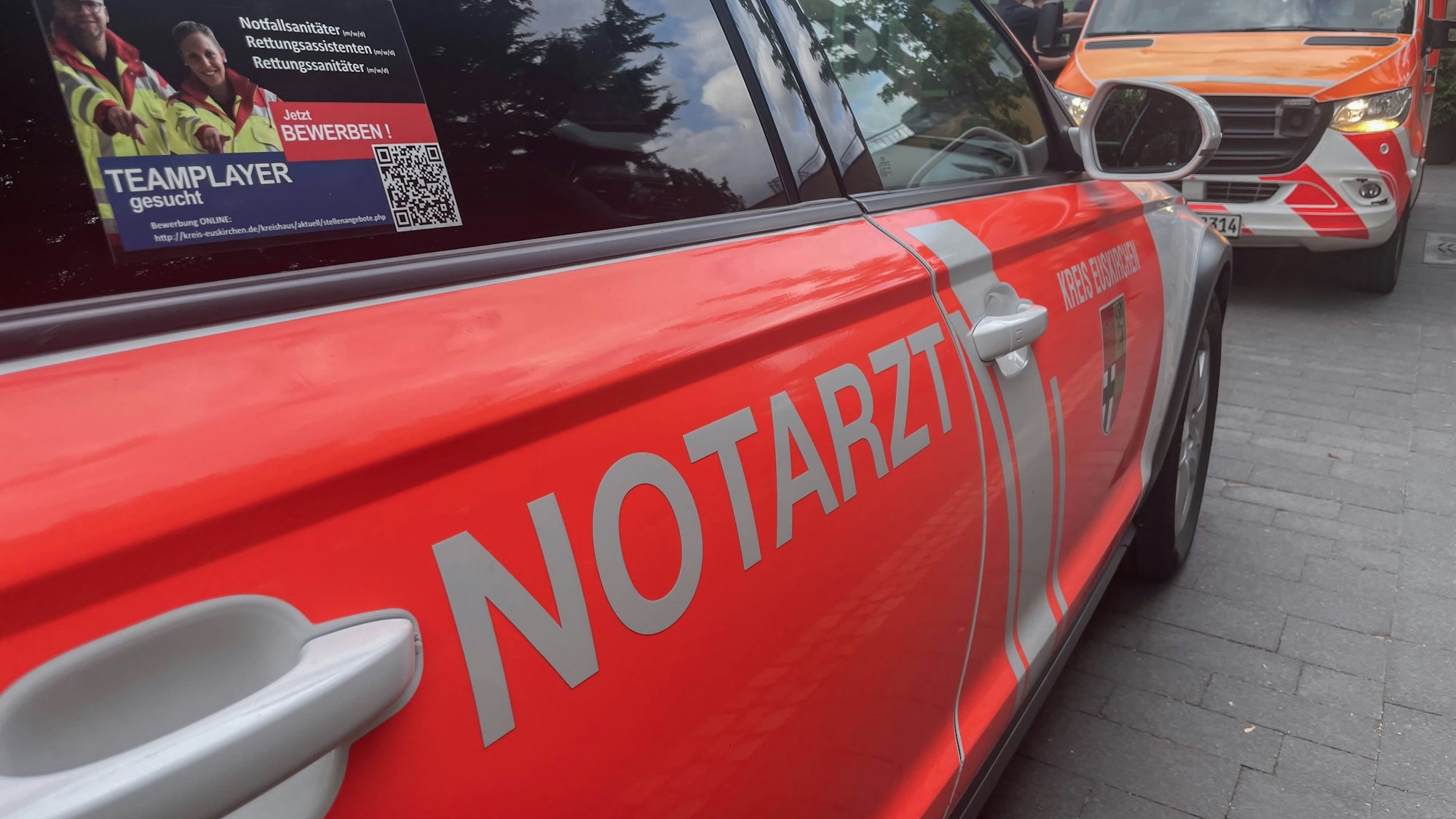 Das Symbolbild zeigt die Beifahrerseite eines Notarzt-Einsatzfahrzeugs aus dem Kreis Euskirchen, im Hintergrund ist ein Rettungswagen zu sehen.