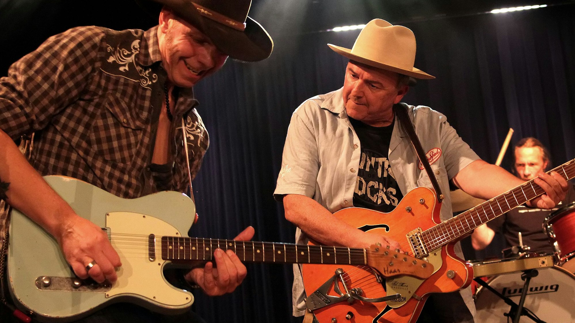 Zwei Musiker von Hillbilly Deluxe mit Gitarre und Cowboy-Hüten.