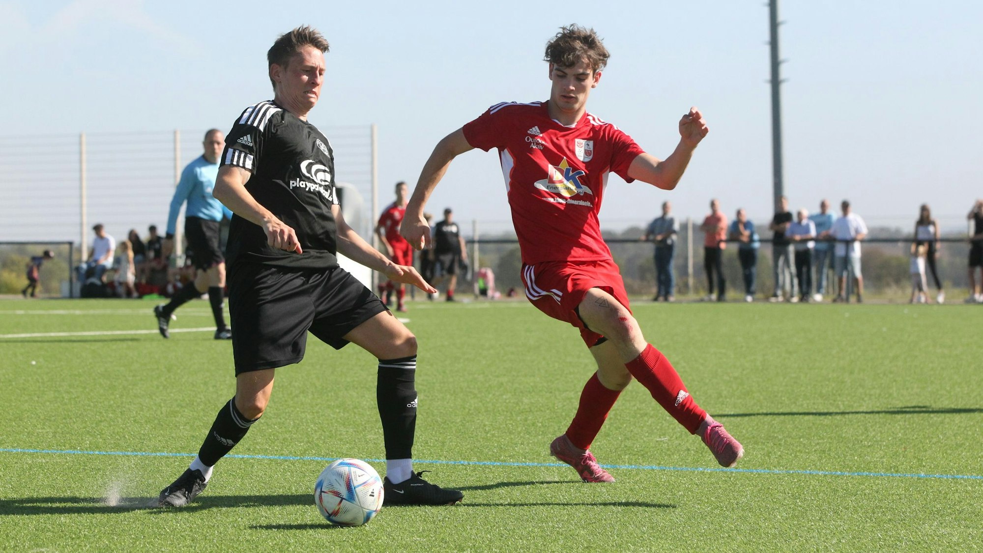 Ein Fußballspieler führt den Ball, von der Seite kommt ein Gegner angelaufen.