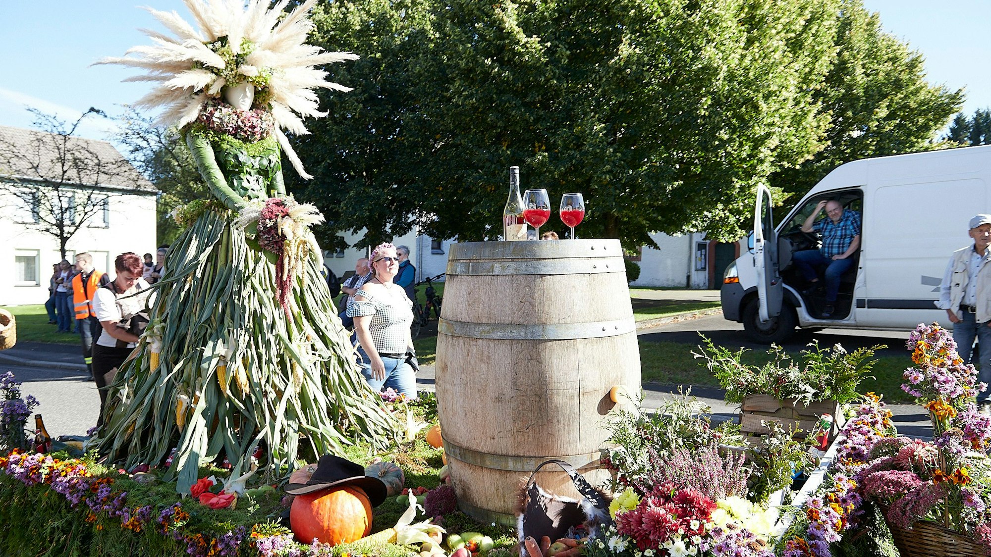 Die Figur einer Erntegöttin auf einem geschmückten Wagen eines Erntedankzugs. Auch ein hölzernes Fass ist zu sehen.