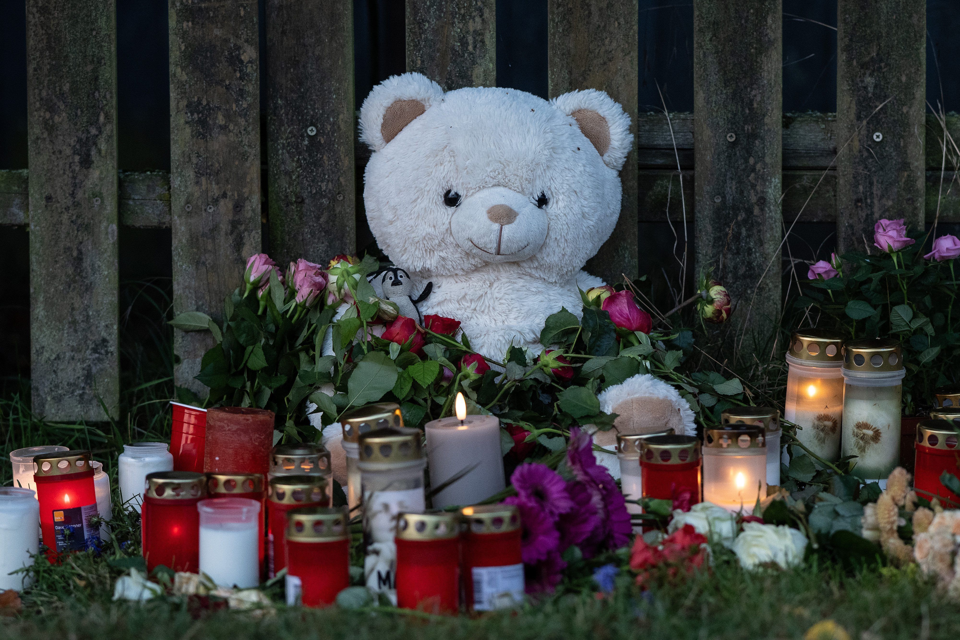 Kerzen, Blumen und ein großer Plüschteddy sind vor einem Zaun am Fundort zu sehen. Am Donnerstag war die Leiche einer vermissten 14-Jährigen aus Nordhessen in einem Waldstück gefunden worden. Die Polizei hat einen Tatverdächtigen festgenommen.