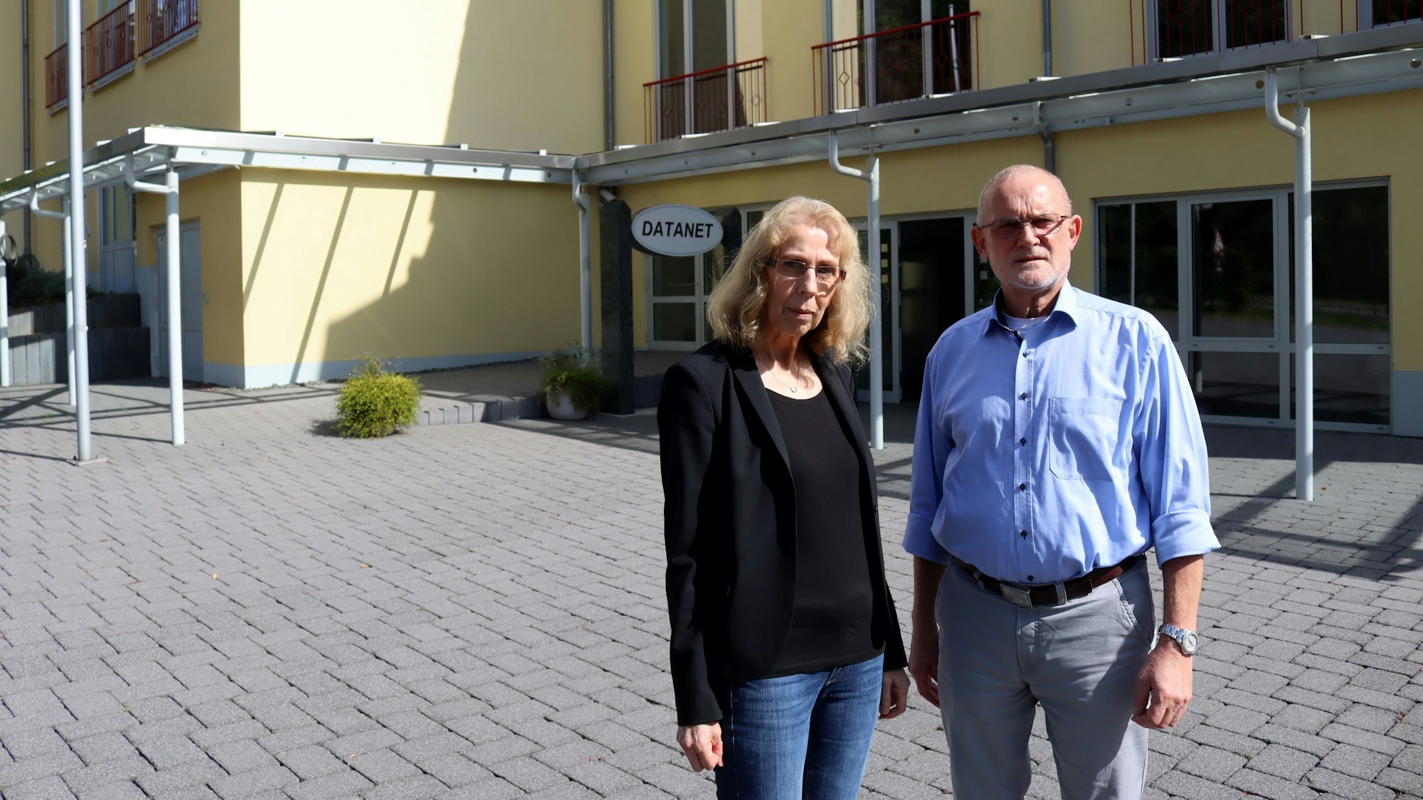 Zwei Firmeninhaber stehen auf dem Parkplatz ihrer Firma, im Hintergrund die Zentrale.