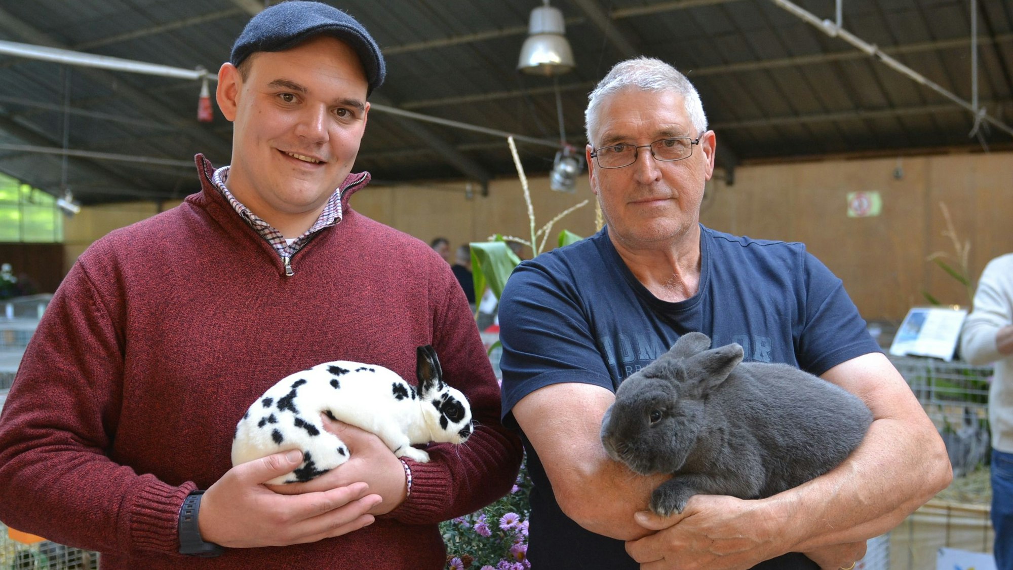 Clubmeister Daniel Bürling und Kreismeister Manfred Kaulich halten ihre Kaninchen auf dem Arm.