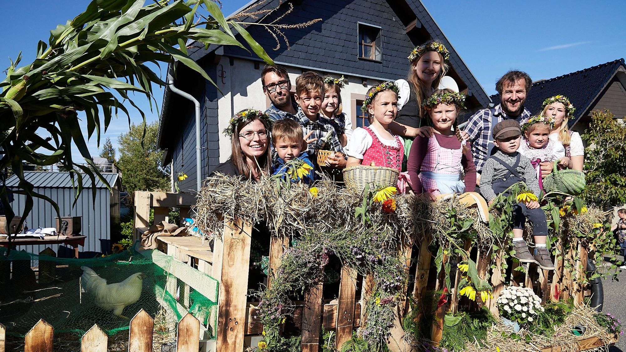 Erwachsene und Kinder auf einem herbstlich geschmückten Anhänger beim Entedankzug in Schöneseiffen und Harperscheid.