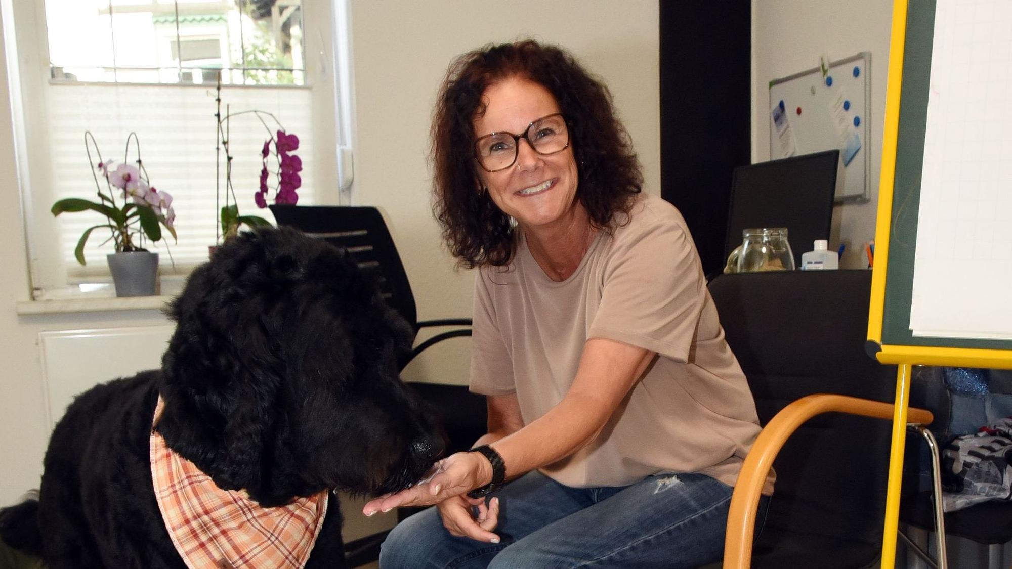 Das Foto zeigt Therapeutin Jutta Schüler und ihren schwarzen Hund Gunnar.