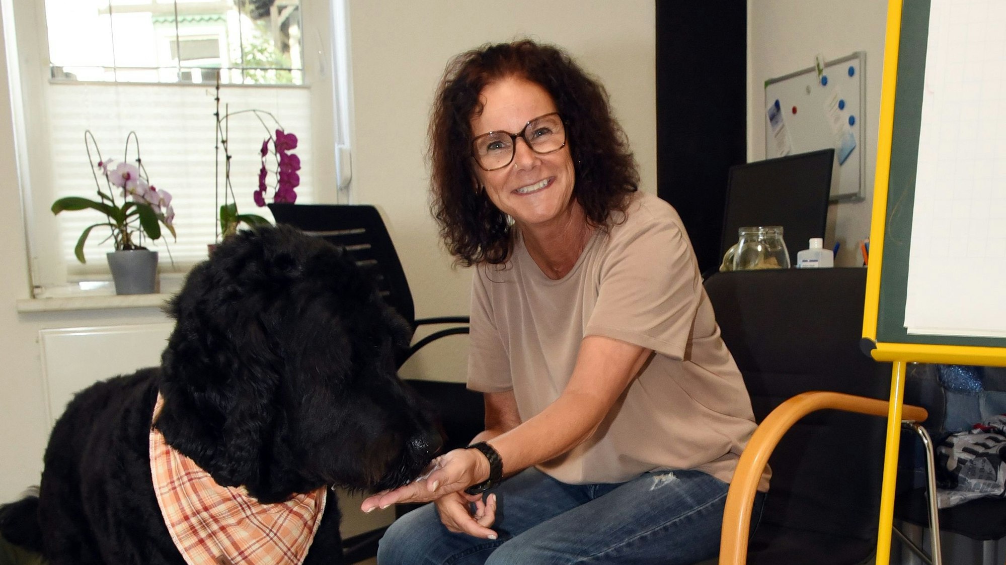 Das Foto zeigt Therapeutin Jutta Schüler und ihren schwarzen Hund Gunnar.