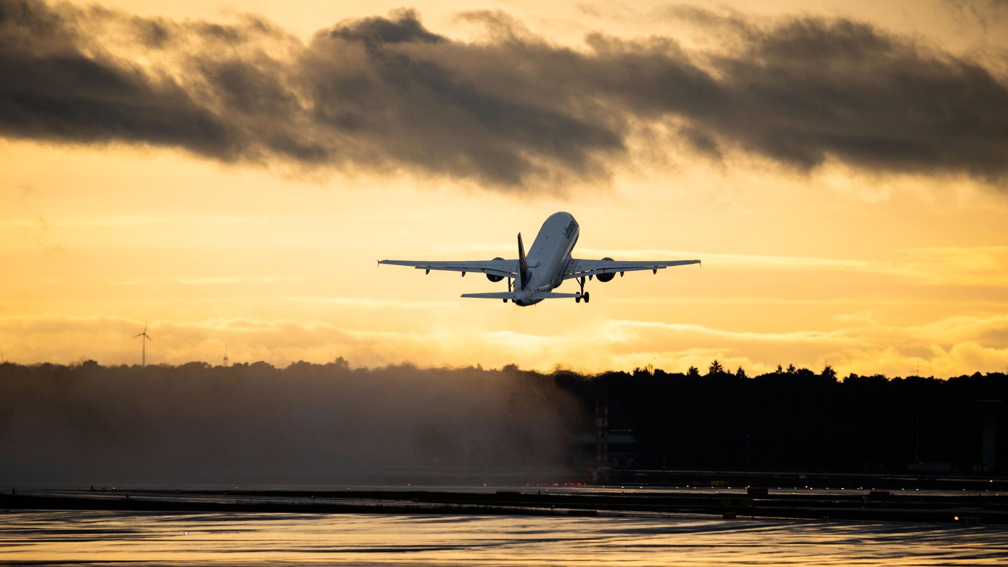 Ein startendes Flugzeug vor einem orangen Abendhimmel.