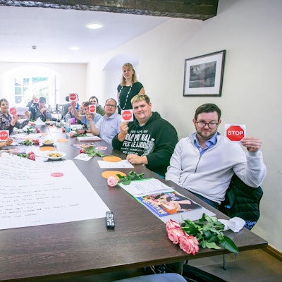 An einem langen Tisch sitzen junge Frauen und Männer.