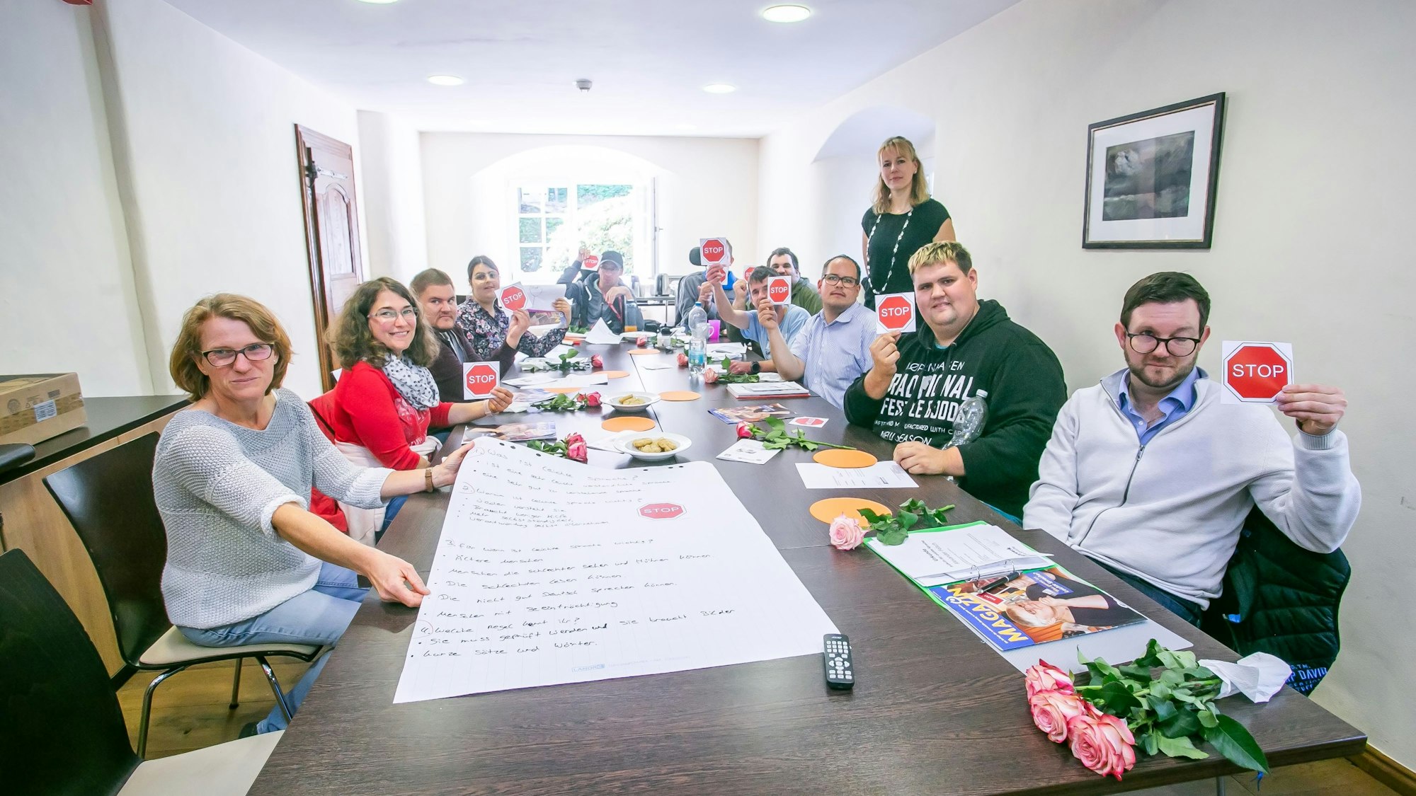 An einem langen Tisch sitzen junge Frauen und Männer.
