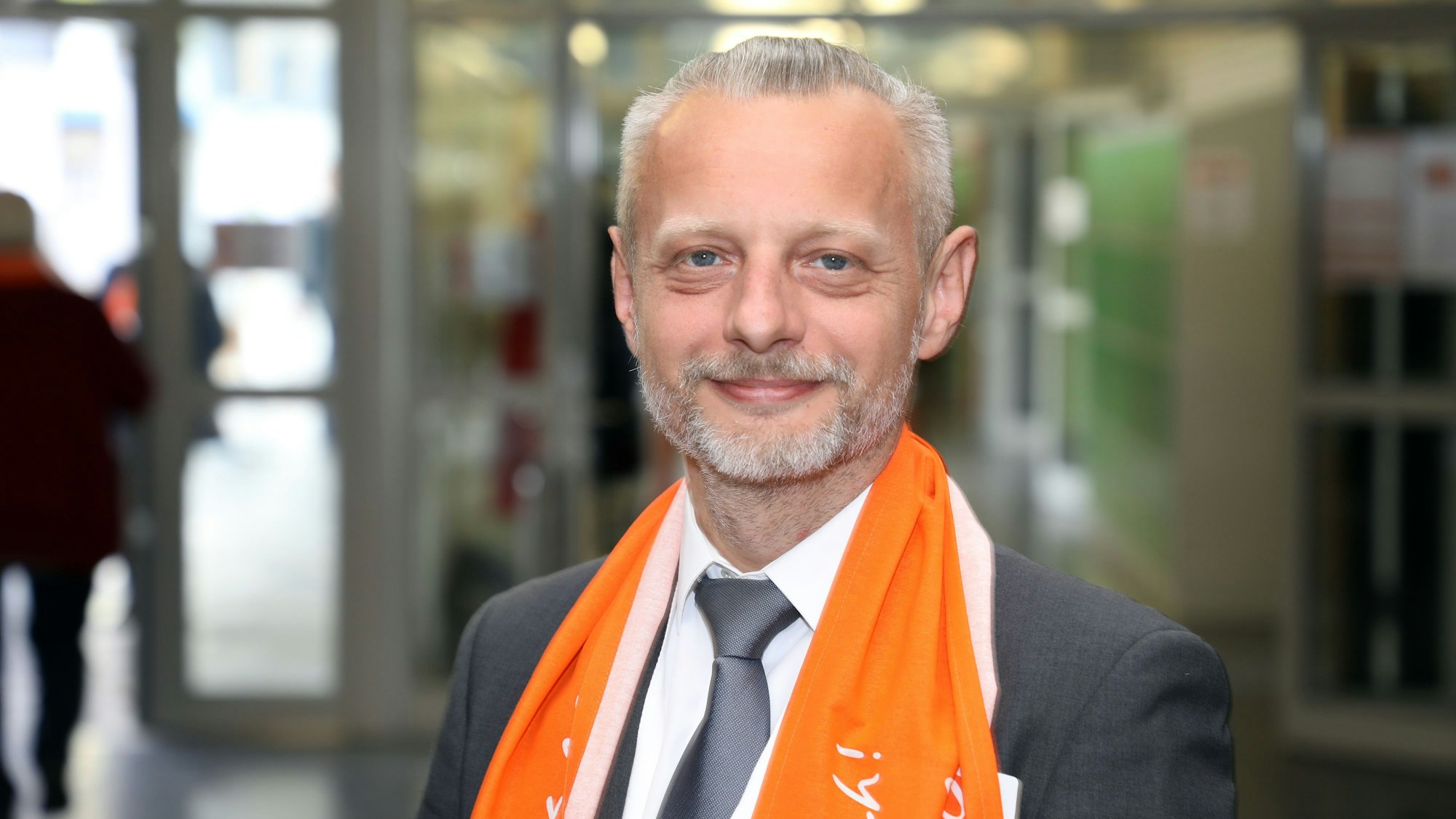 Ein Mann mit Kolping-Schal steht im Foyer der Aula des Albertus-Magnus-Gymnasiums in Bensberg.
