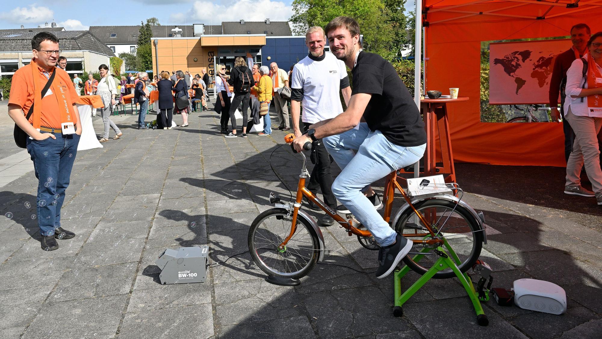 Ein Mann sitzt auf einem Fahrrad und treibt einen Dynamo an.