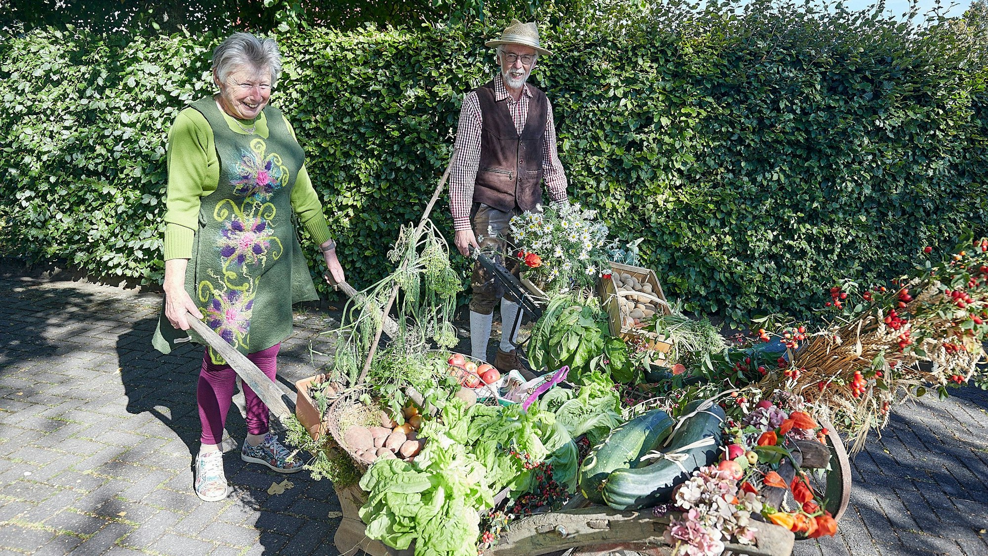 Agnes Wauben und Herbert Gerhards mit zwei alten Schubkarren, die mit Erntefrüchten beladen sind.