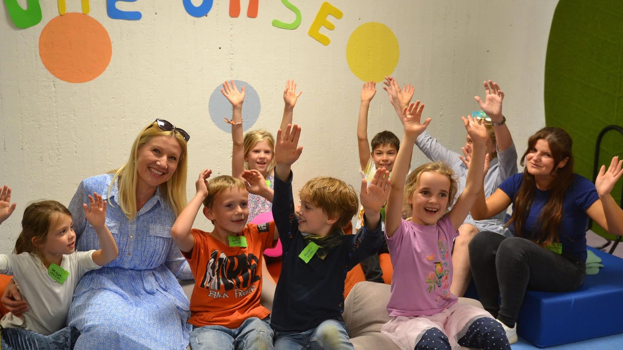 Kinder und Lehrkräfte heben jubelnd die Arme.