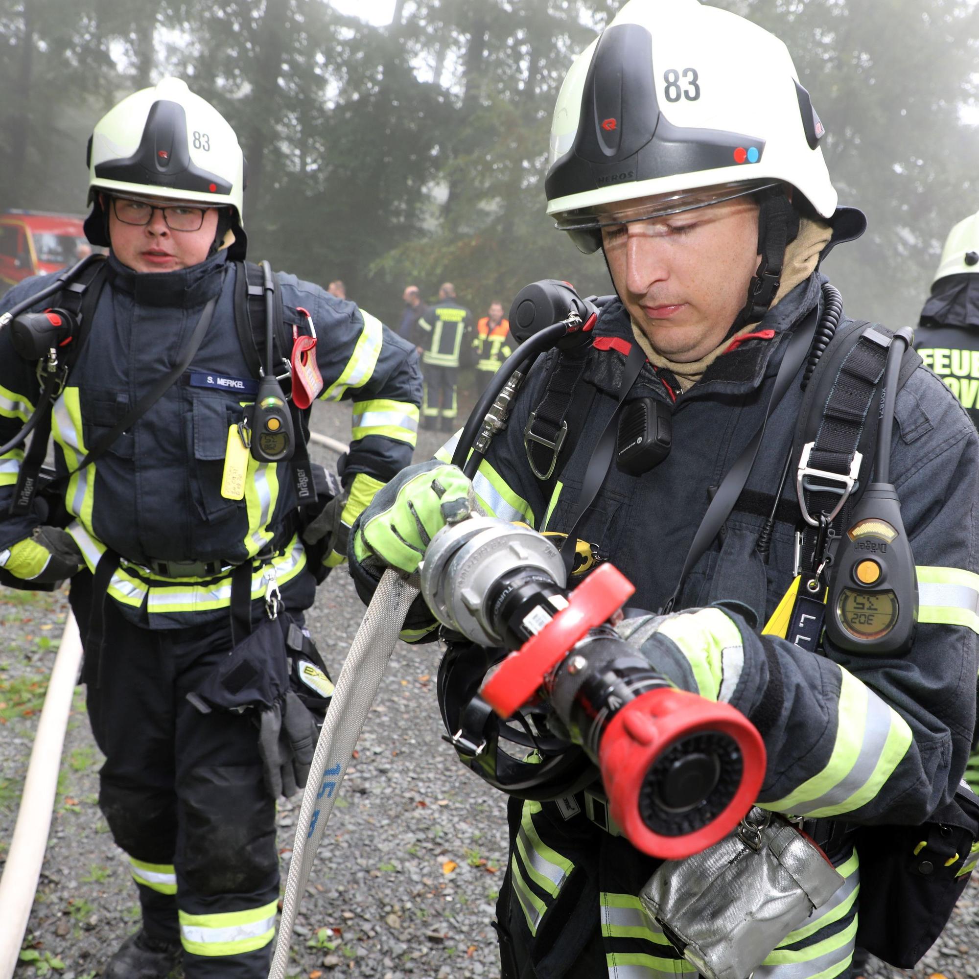 Zwei Feuerwehrleute montieren eine Düse an einen Feuerwehrschlauch.