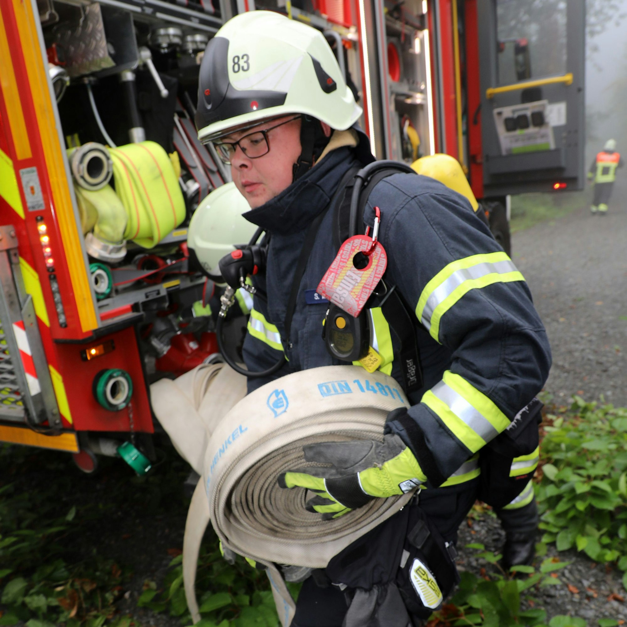 Ein Feuerwehrmann holt einen Schlauch von einem Einsatzfahrzeug.