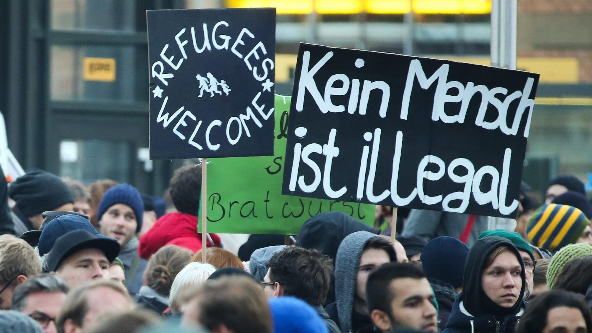 Demonstranten mit den Plakaten „Kein Mensch ist illegal“ und „Refugees welcome“ haben sich in bei einer Demonstration versammelt. (Archivbild)