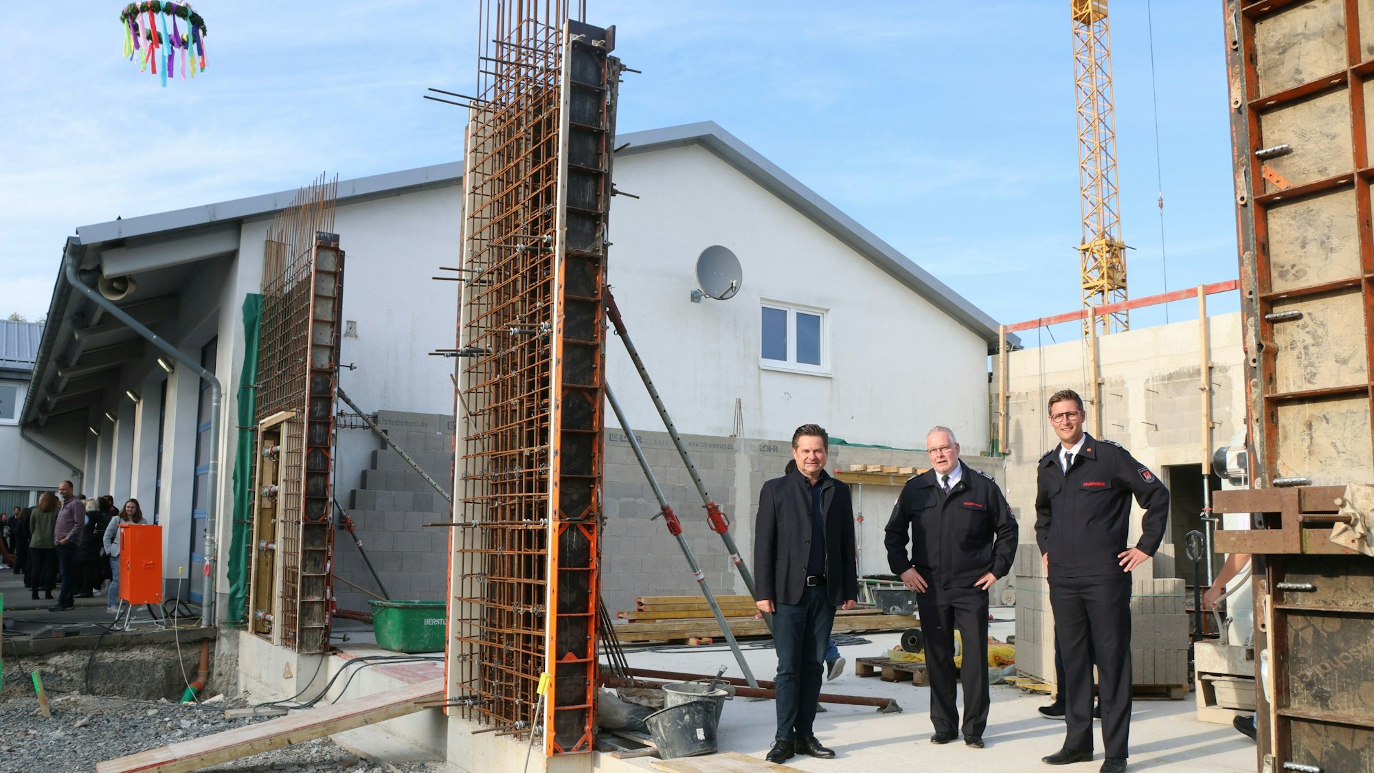 Drei Männer stehen vor einem im Bau befindlichen Gebäude.