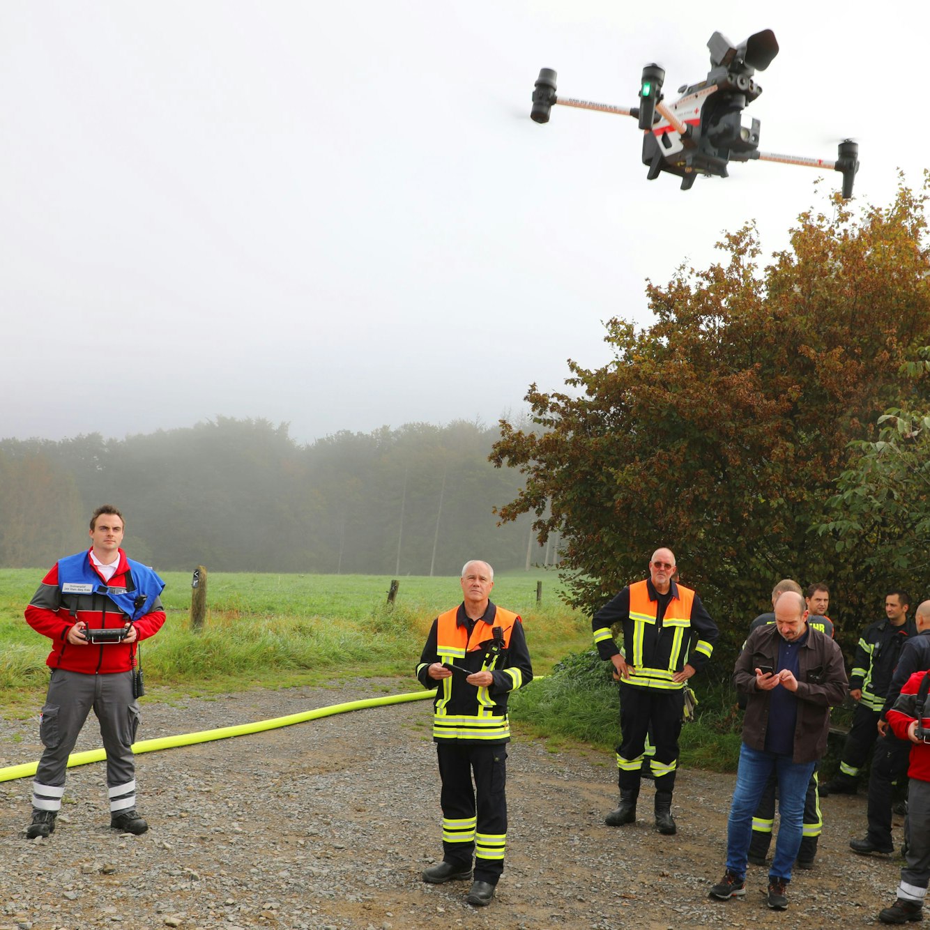 Ein DRK-Helfer mit blauer Weste und Fernsteuerung lässt eine Frohne aufsteigen. Feuerwehrleute sehen ihr nach.