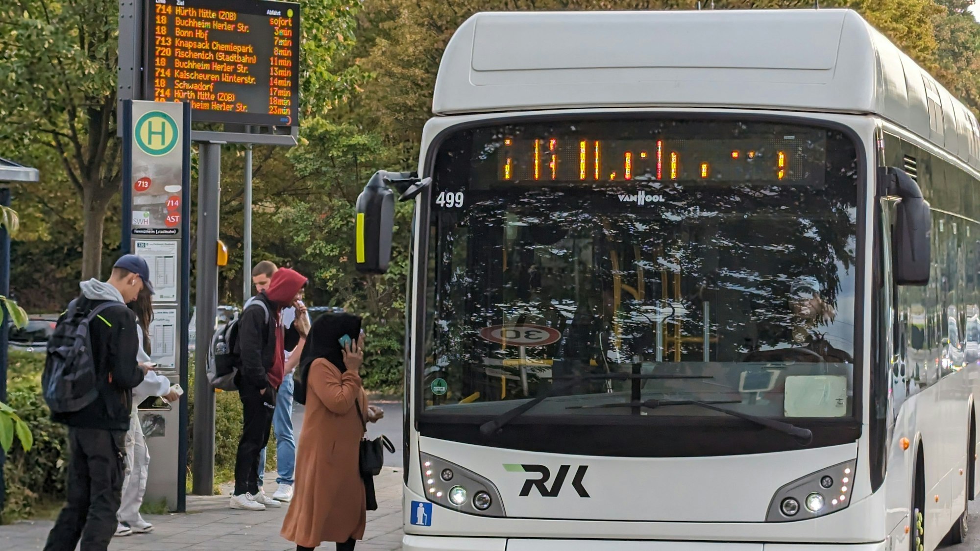 Ein Bus steht an einer Bushaltestelle, an der Fahrgäste warten.