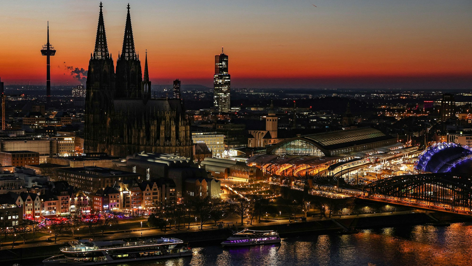 Der Himmel färbt sich hinter dem Rheinpanorama mit Dom (M.) und Hauptbahnhof (r.) nach Sonnenuntergang rötlich.
