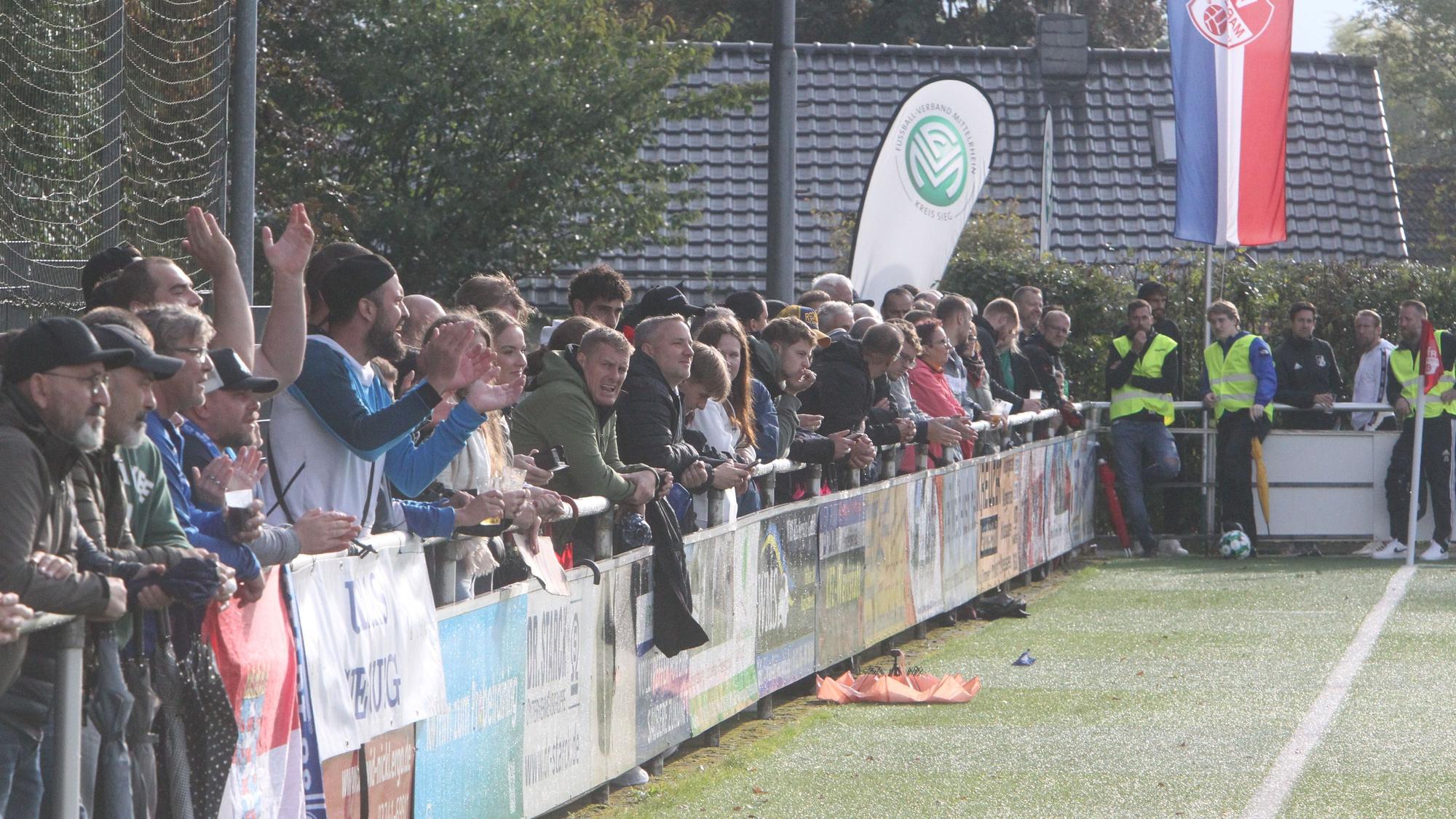Menschen stehen am Rand eines Fußballplatzes.