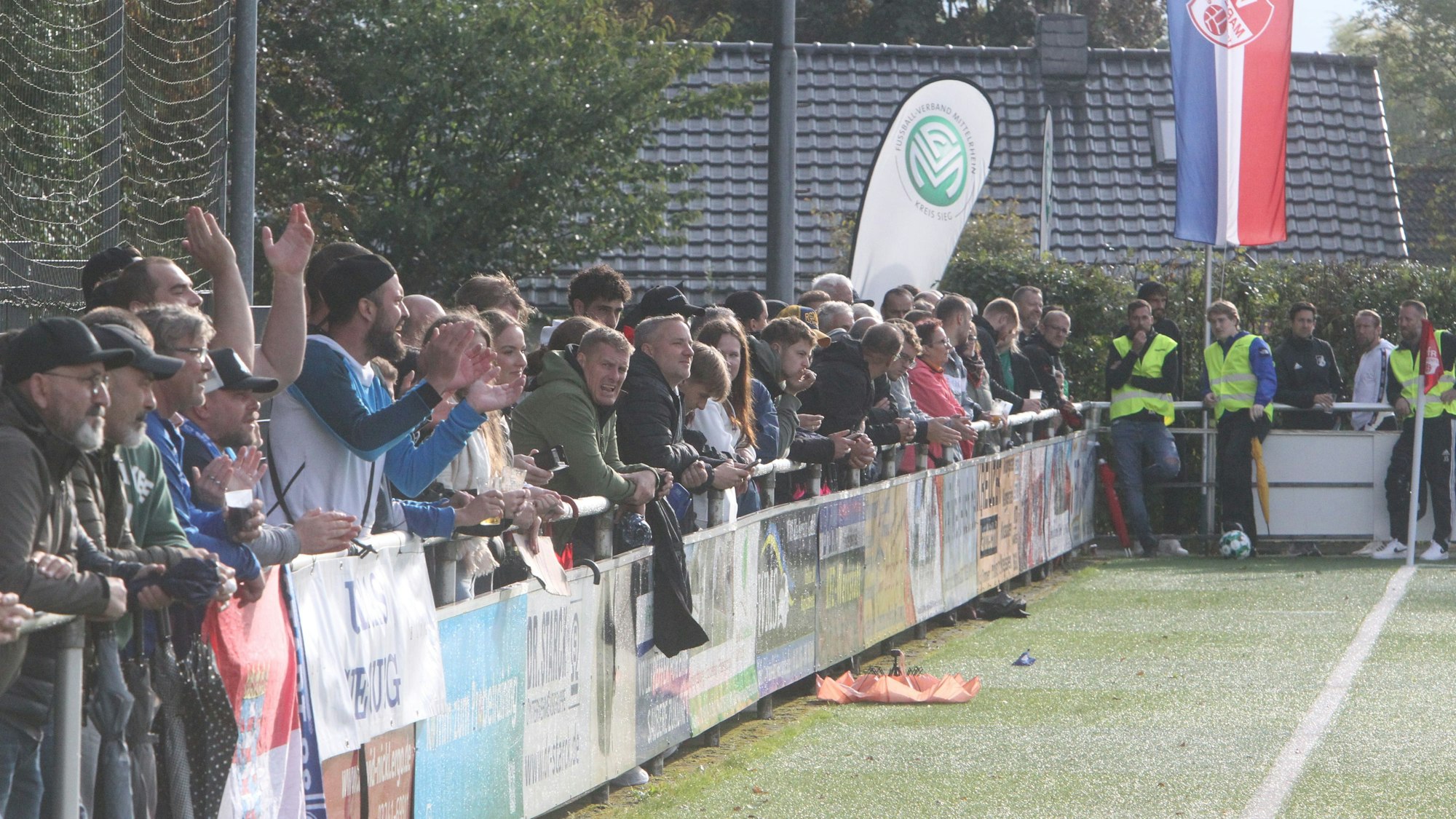 Menschen stehen am Rand eines Fußballplatzes.