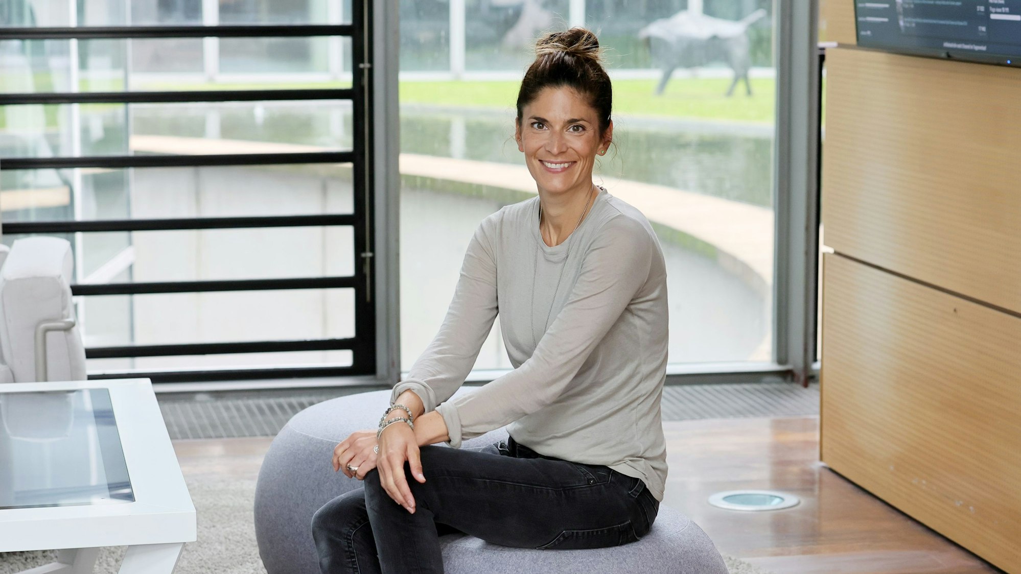 Katty Salié sitzt auf einem Filz-Pouf im Foyer der Redaktion.