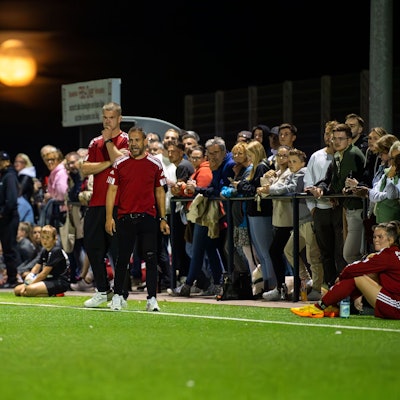 Zuschauer stehen direkt hinter dem Zülpicher Trainerduo am Spielfeldrand. Im Hintergrund der blutrote Mond.