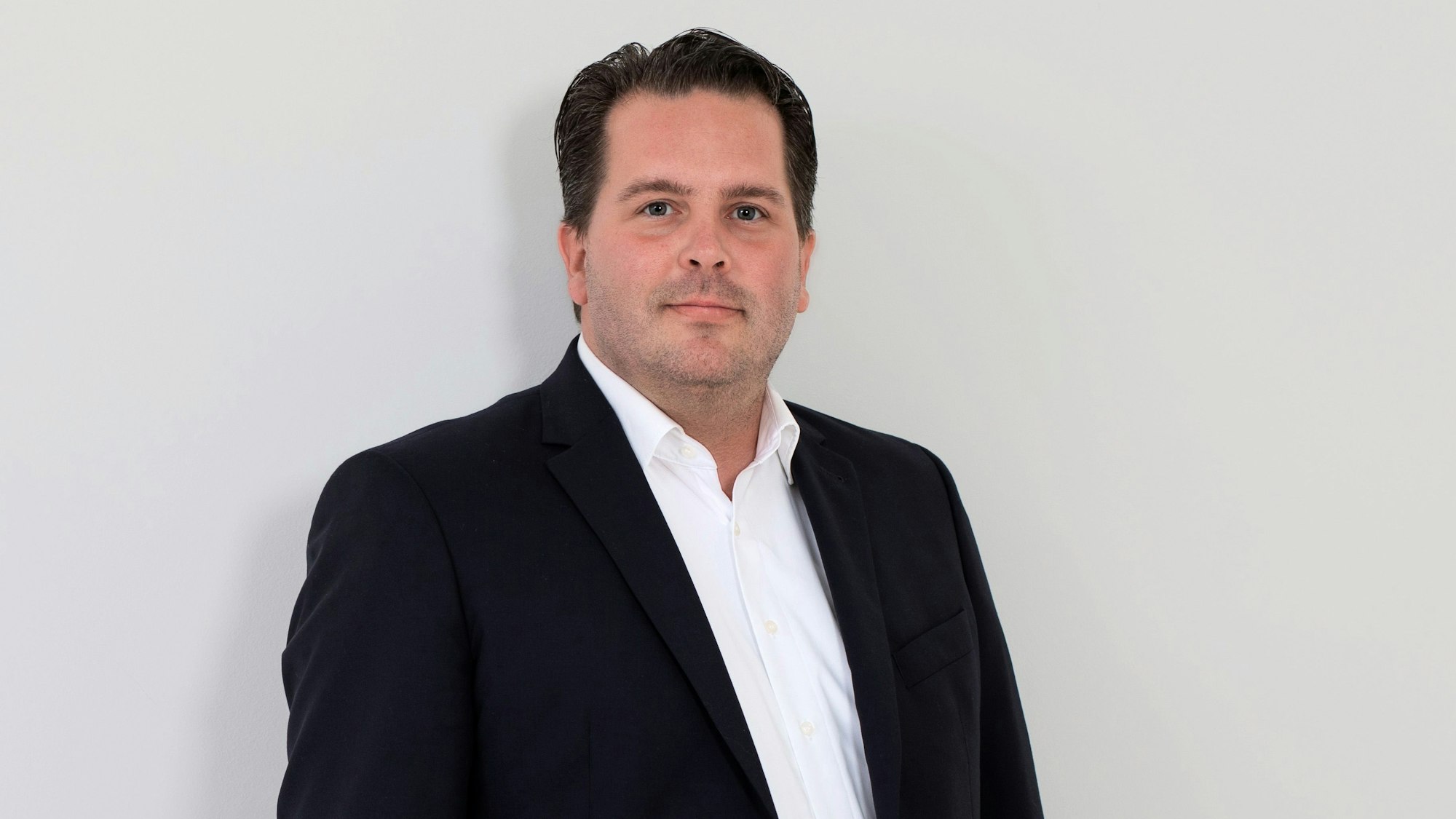 Der neue Geschäftsführer des Evangelischen Krankenhauses Bergisch Gladbach, Sebastian Haeger, steht vor einer weißen Wand.