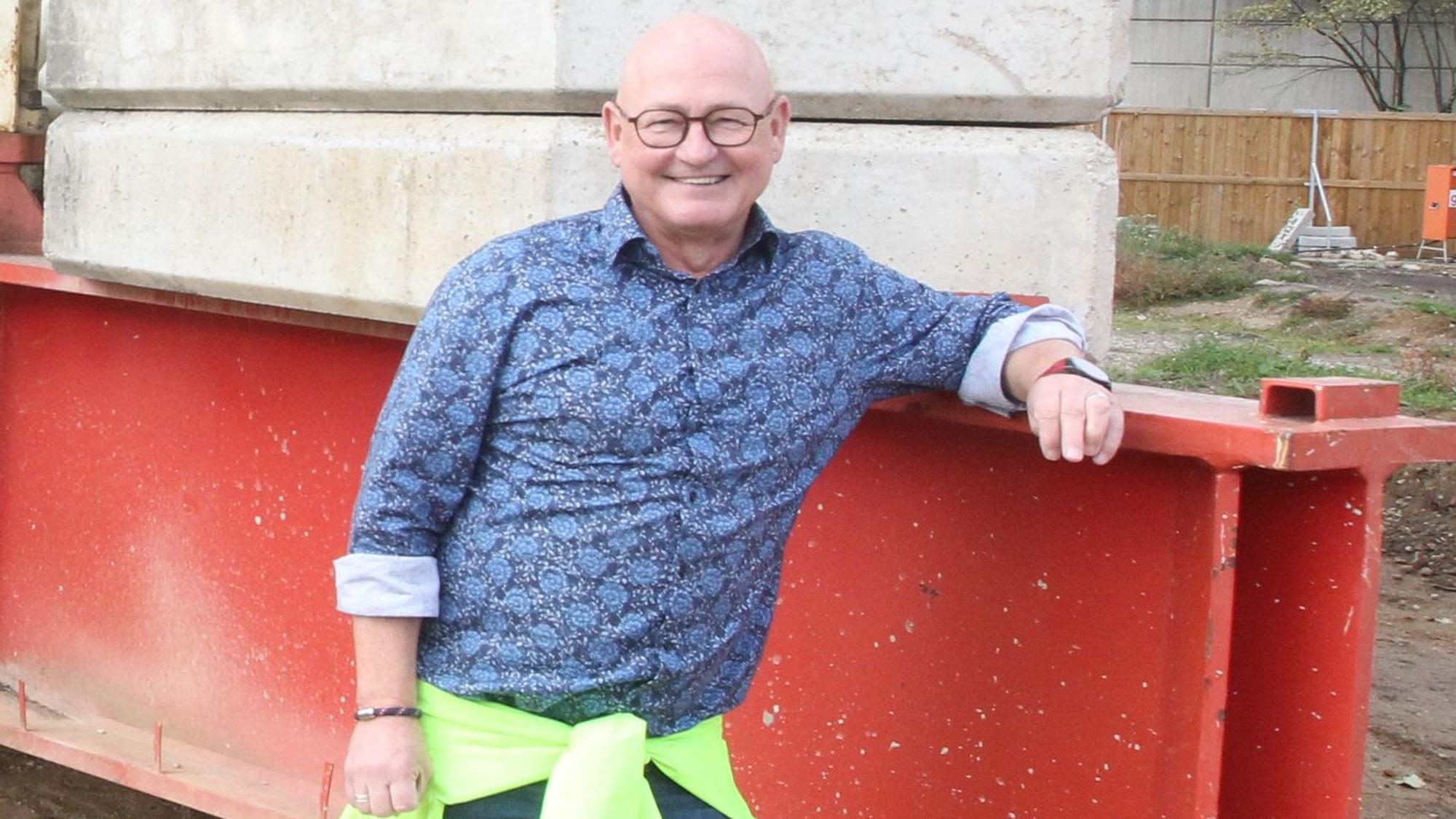 Ein Mann in blauem Hemd lehnt an einem Kran