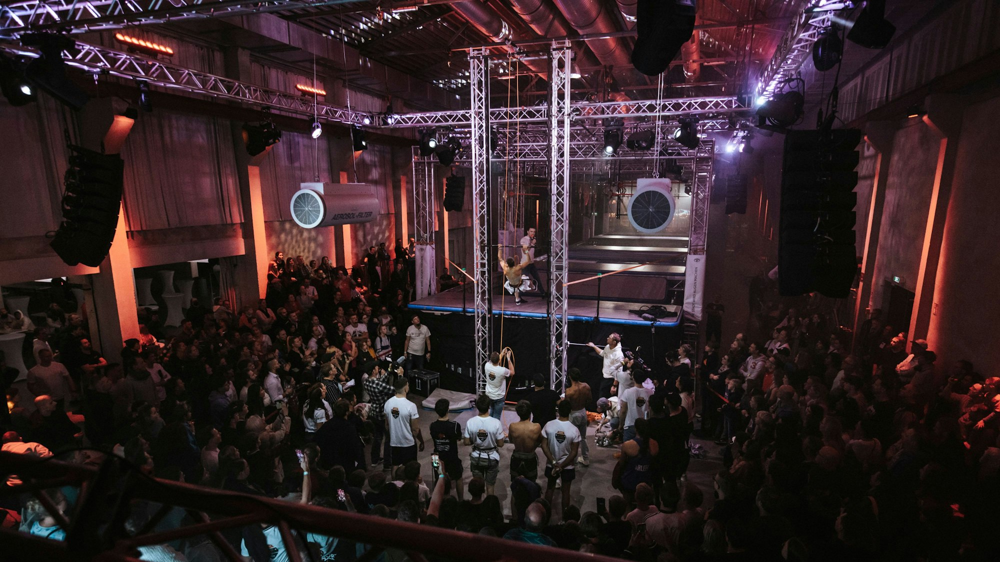 Ein Athlet absolviert einen Parcours, Menschen schauen ihm zu.