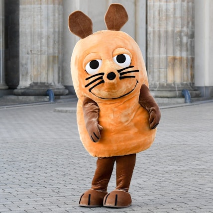 Eine „Maus“-Figur steht vor dem Brandenburger Tor.