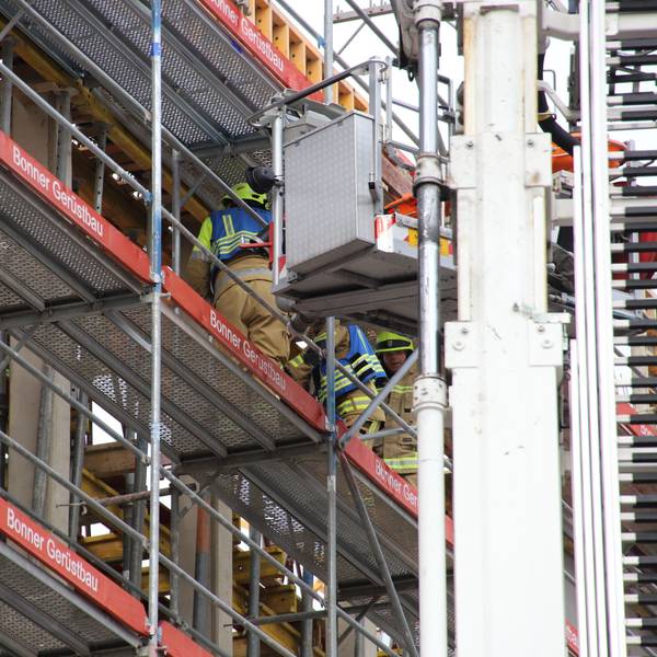 Auf der Baustelle des neuen Gerichtsgebäudes für die Cum-Ex-Prozesse ist ein 64 Jahre alter Bauarbeiter schwer verletzt worden. Feuerwehrmänner schieben ihn auf einer Schlleifkorbtrage auf den Korb des Teleskopmasts.