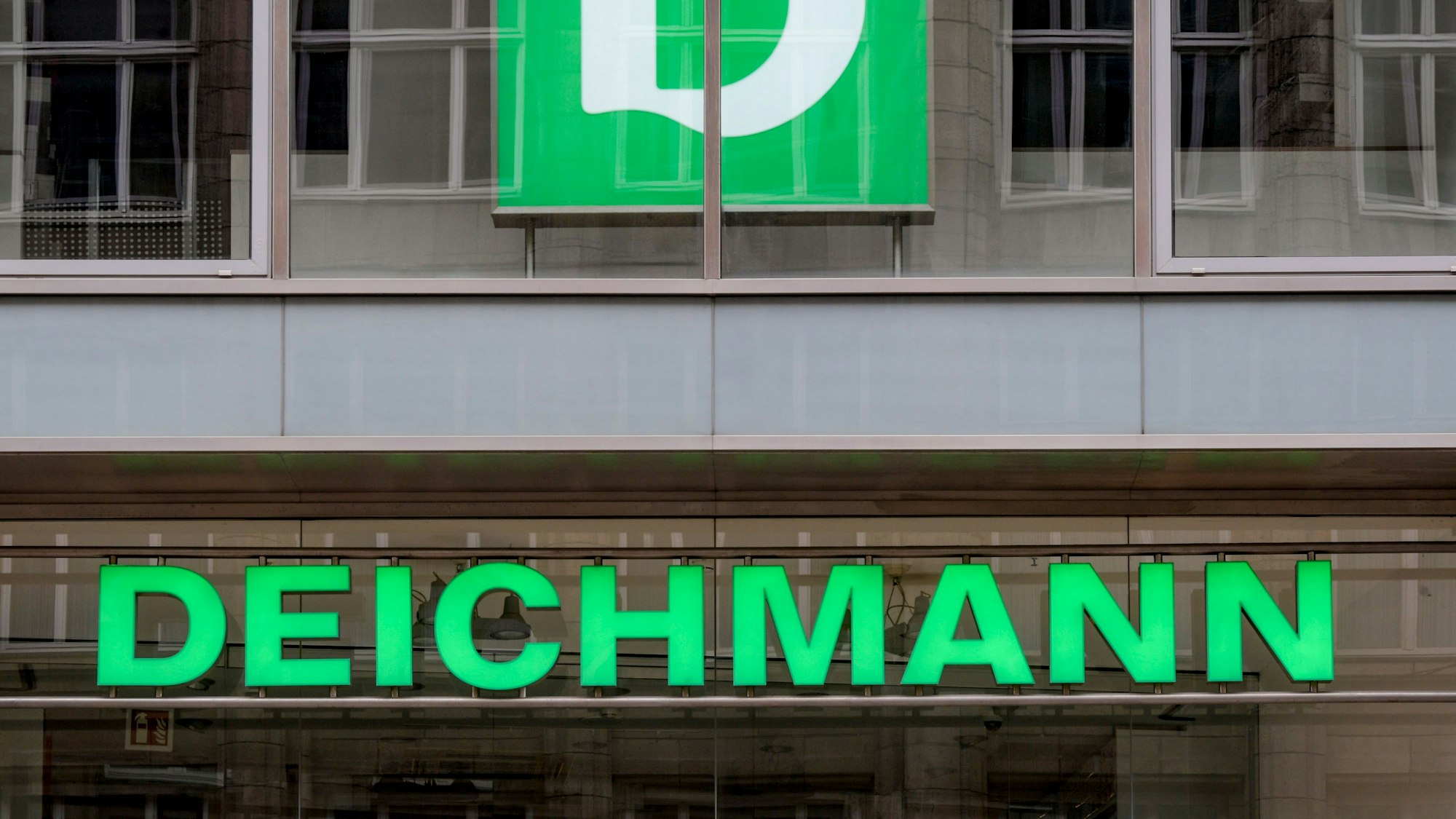 Das Logo der Schuhkette Deichmann hängt über dem Eingang einer Filiale.