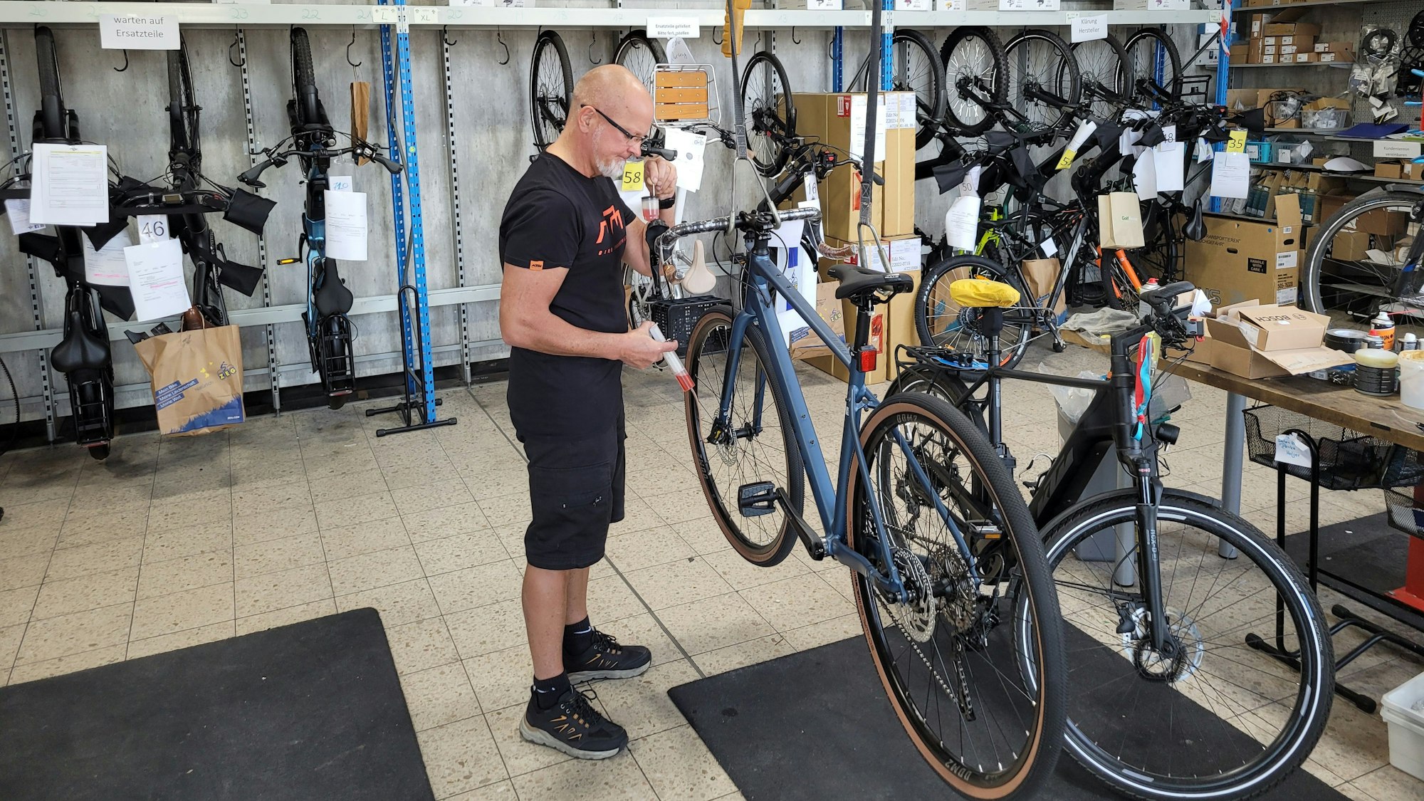 Ein Mitarbeiter bearbeitet die Bremsen eines Fahrrades.