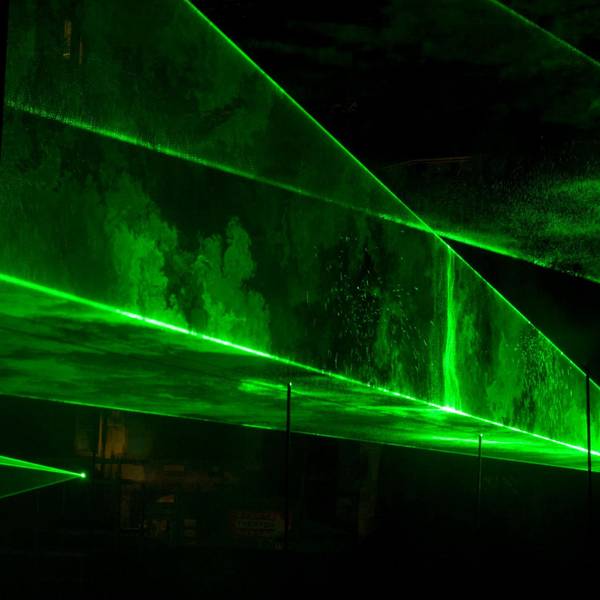 Grüne Laserstrahlen bilden treppenartige Strukturen in der Dunkelheit.