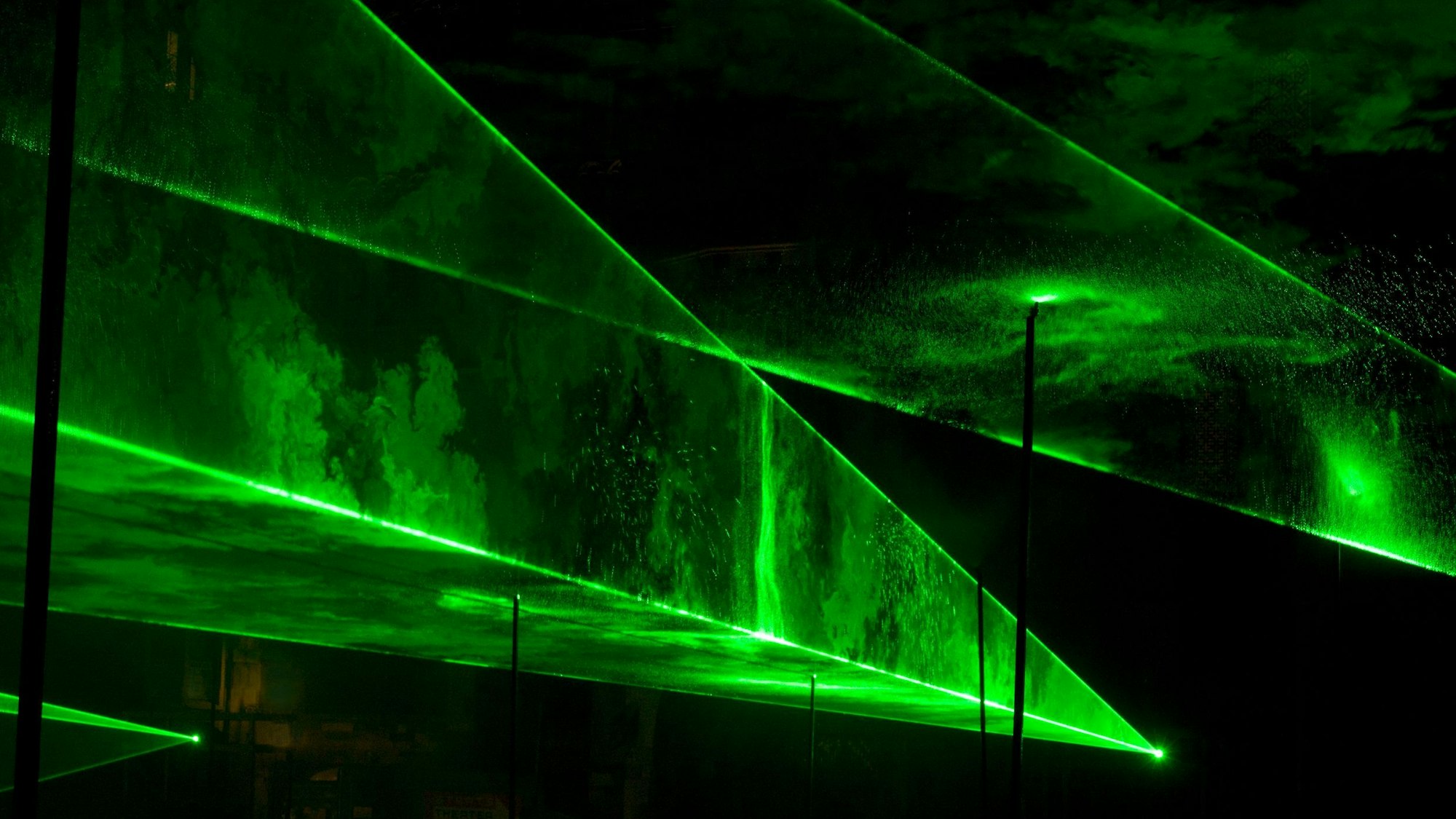 Grüne Laserstrahlen bilden treppenartige Strukturen in der Dunkelheit.