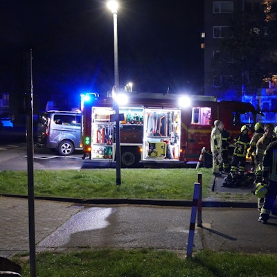 Feuerwehrleute stehen vor dem betroffenen Hochhaus in Niederpleis.